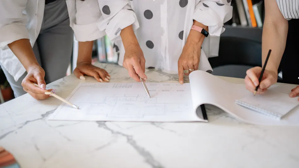 Architectes collaborant autour de plans techniques, analysant les détails d’un projet de construction ou de rénovation pour optimiser l’espace et la conception.