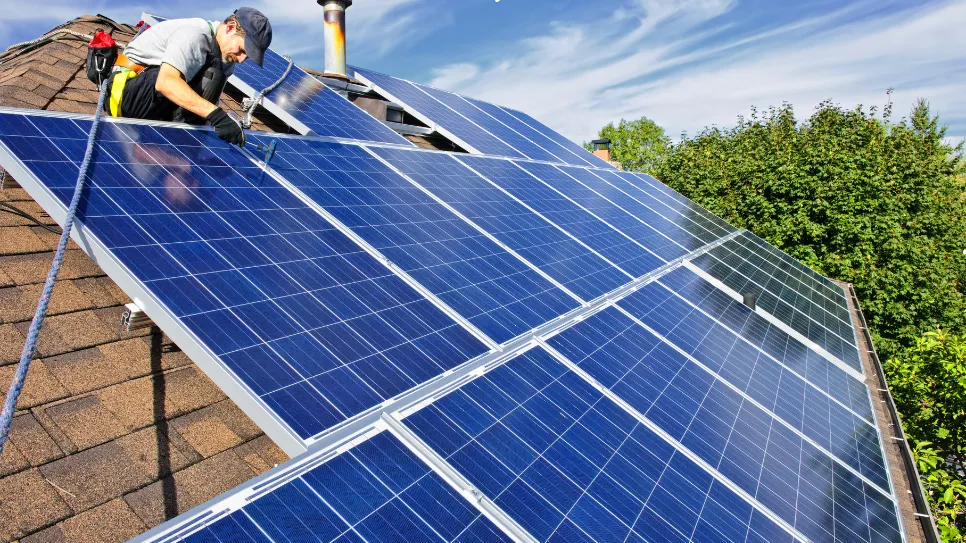 Installation de panneaux solaires sur le toit d’une maison par un technicien.